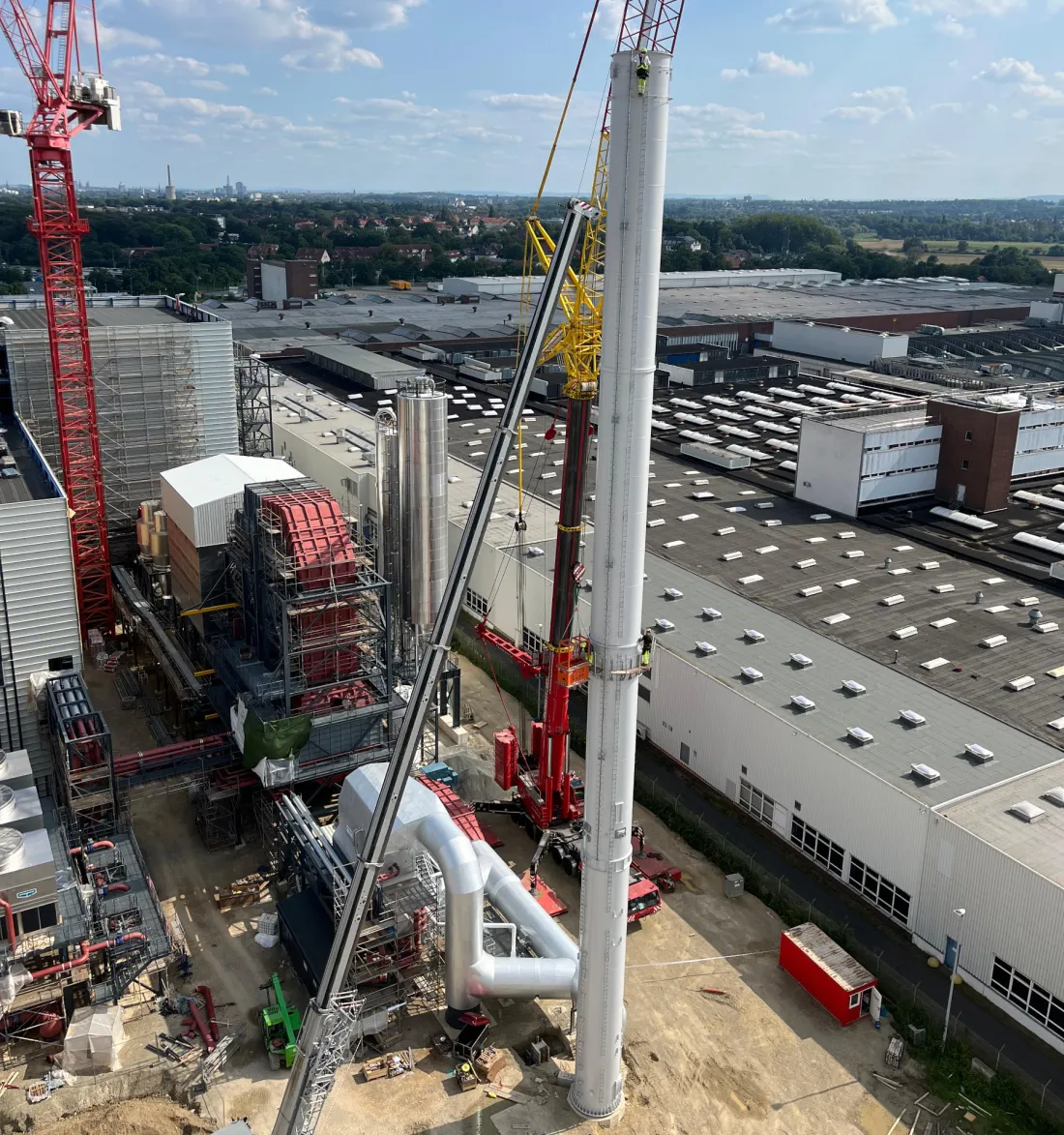 Montagearbeiten an einer hohen Industrieanlage mit Kranunterstützung